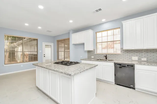 a kitchen with a stove a sink a center island and windows