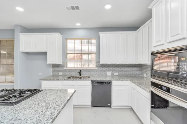 a kitchen with stainless steel appliances kitchen island granite countertop a sink stove and cabinets