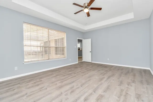 a view of an empty room with a window and wooden floor