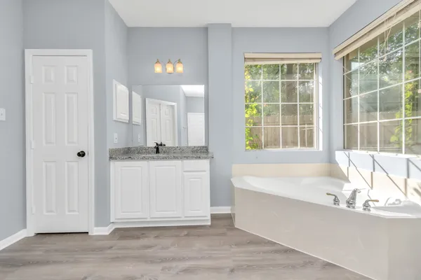a bathroom with a tub a sink and a window