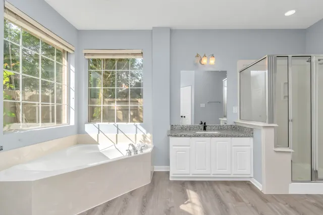 a spacious bathroom with a granite countertop tub sink and mirror