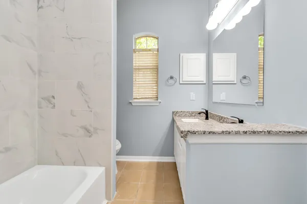 a bathroom with a granite countertop sink a toilet a mirror and shower