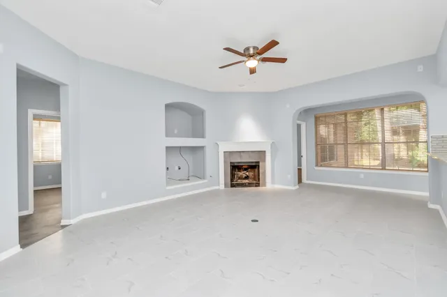 an empty room with windows and fireplace