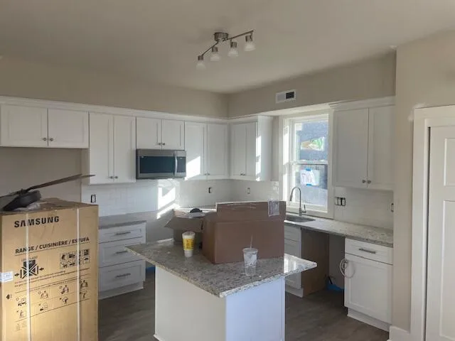 a kitchen with granite countertop a sink stove and cabinets
