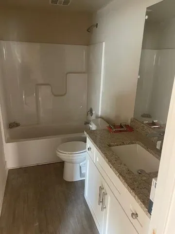 a bathroom with a granite countertop sink a toilet and bathtub
