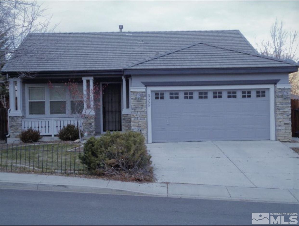 a front view of a house with garage and plants