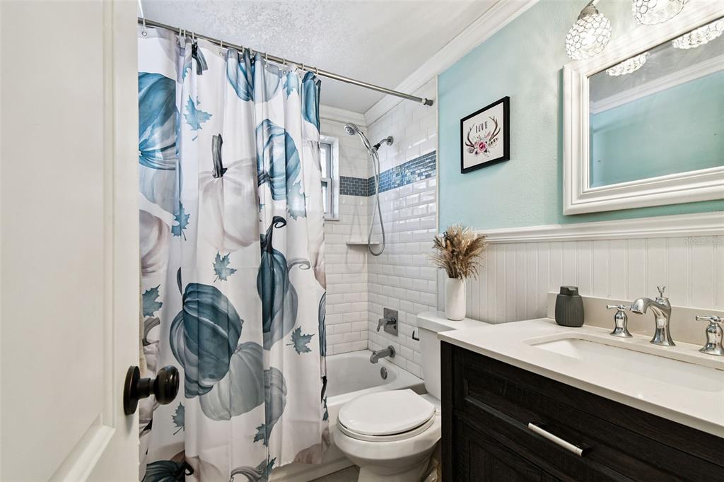 5831 1st Avenue New Port Richey, FL 34652 - Photo 12 of 22 a bathroom with a granite countertop sink a toilet and a shower curtain