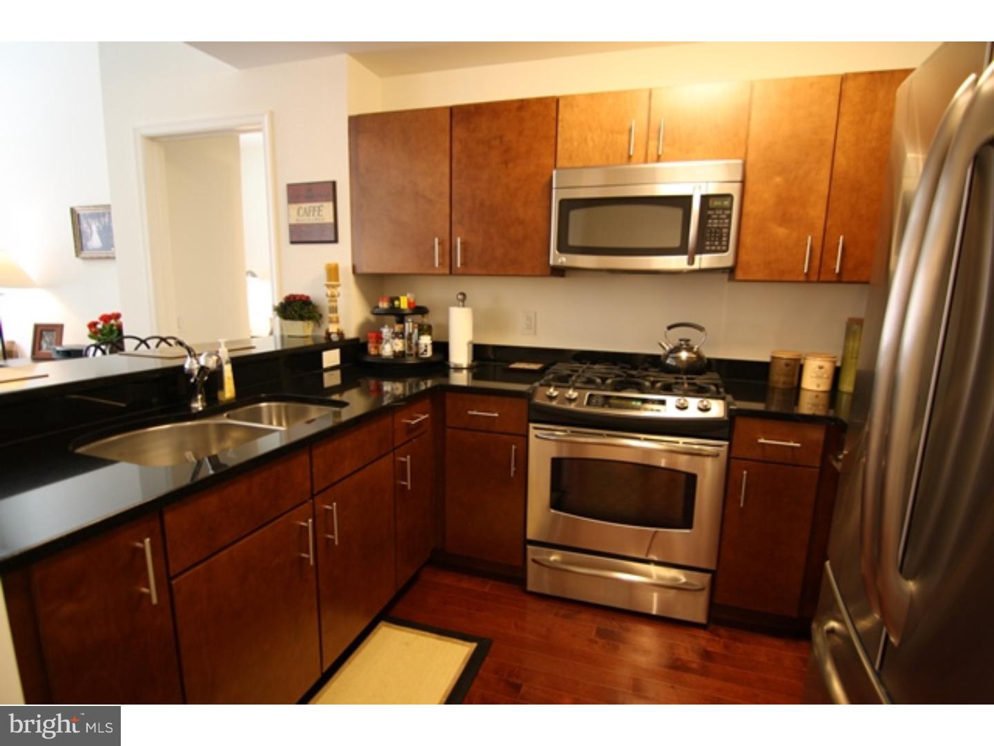a kitchen with stainless steel appliances a stove a sink a microwave a refrigerator and cabinets