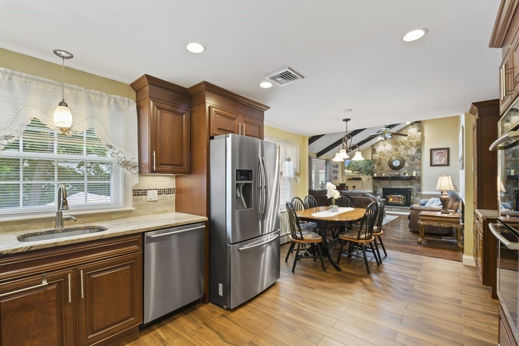 33 Old Farm Road Reading, MA 01867 - Photo 15 of 42 a kitchen with stainless steel appliances a dining table chairs refrigerator and sink