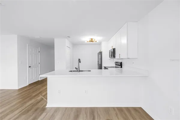 a view of a kitchen with a sink a ceiling fan and kitchen floor