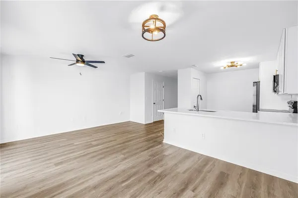 a view of kitchen and empty room with wooden floor