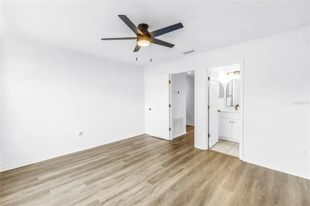 a view of empty room with wooden floor and fan