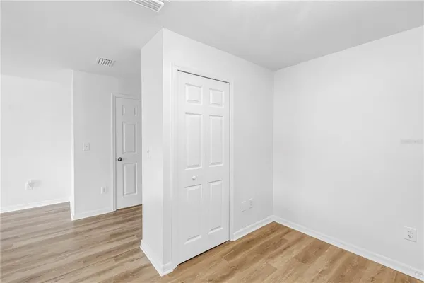 an empty room with wooden floor ceiling fan and windows