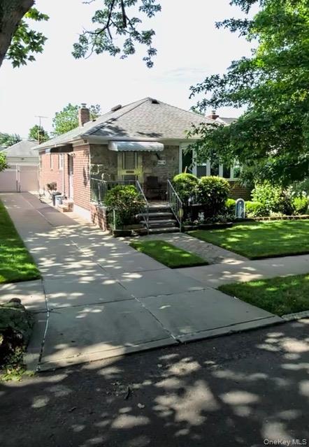 View of front of home with brick siding, a chimney, and a front lawn