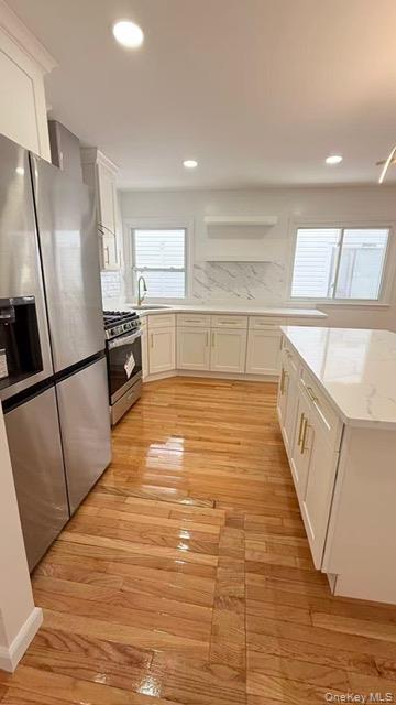 151-28 24th Road Queens, NY 11357 - Photo 6 of 8 Kitchen with white cabinetry, appliances with stainless steel finishes, light wood-type flooring, recessed lighting, and decorative backsplash