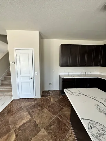 a view of an empty room with kitchen and wooden floor