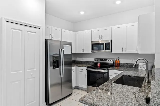 a kitchen with granite countertop a refrigerator and a sink