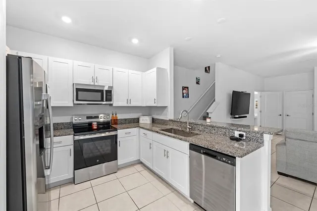 a kitchen with stainless steel appliances granite countertop a stove top oven a refrigerator a sink and dishwasher