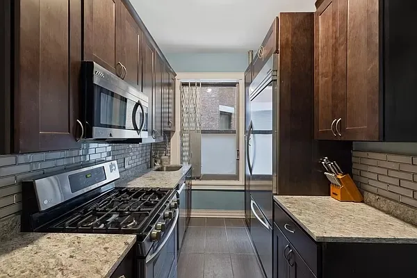 a kitchen with granite countertop a sink stove and refrigerator
