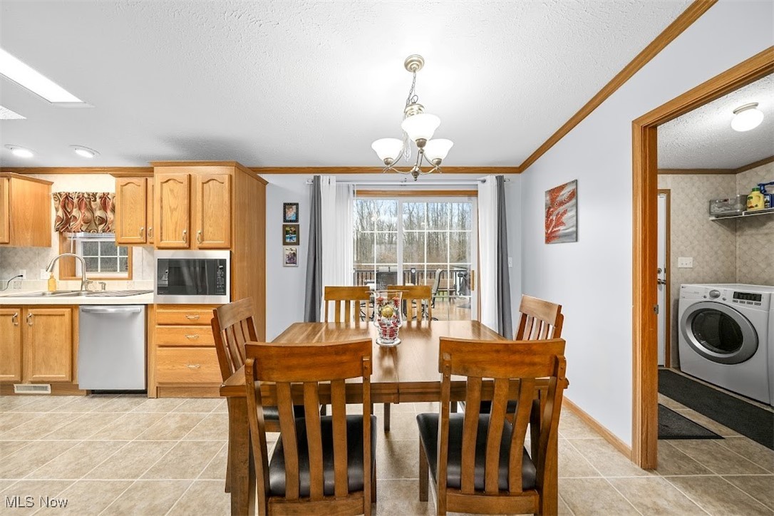 17296 Old State Road Middlefield, OH 44062 - Photo 10 of 44 Kitchen with stainless steel appliances, sink, pendant lighting, an inviting chandelier, and washer / dryer