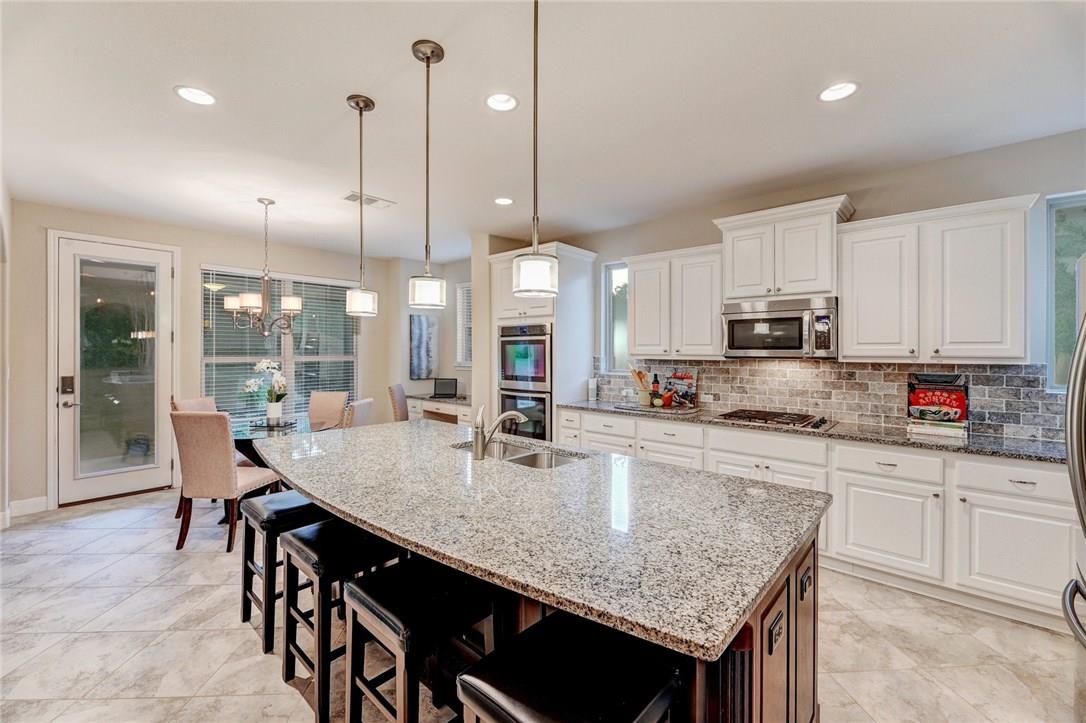 a kitchen with stainless steel appliances granite countertop a kitchen island a stove a table and chairs in it