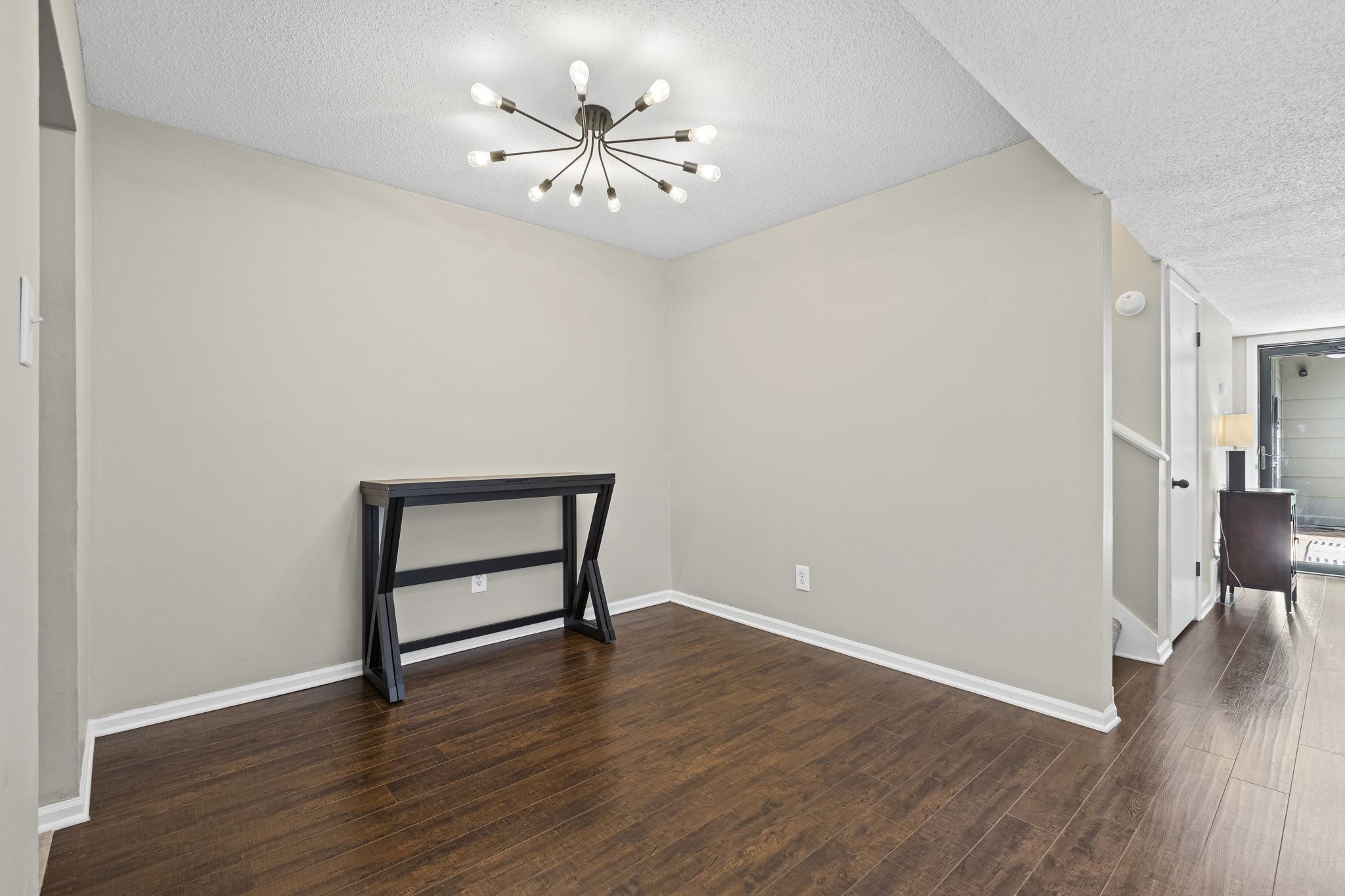 1942 Allenby Road Germantown, TN 38139 - Photo 9 of 34 Empty room with a textured ceiling, dark wood-style flooring, and suspended lighting