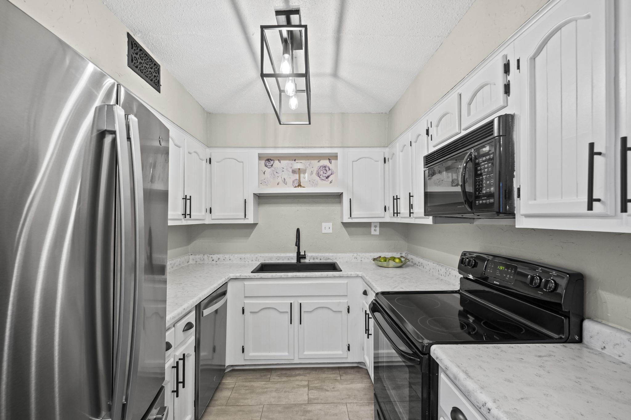 1942 Allenby Road Germantown, TN 38139 - Photo 10 of 34 Kitchen with black appliances, white cabinets, a textured ceiling, and light countertops