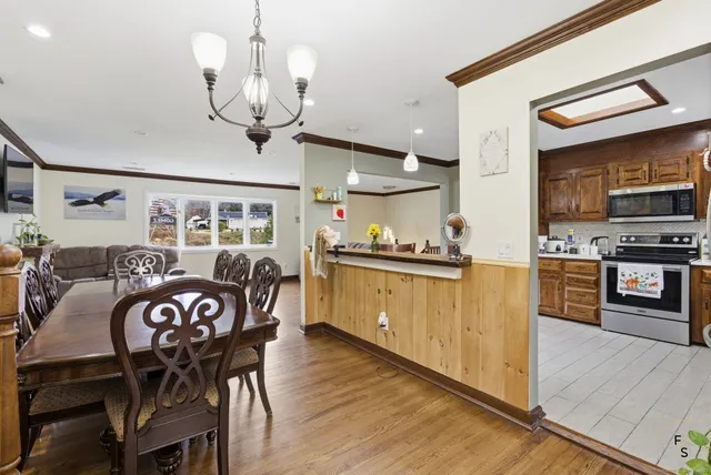 a kitchen with stainless steel appliances kitchen island granite countertop a table chairs and a refrigerator
