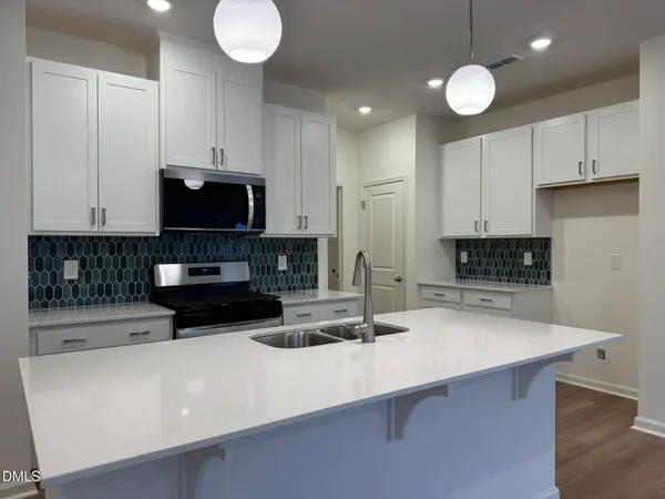 a kitchen with kitchen island granite countertop a sink a stove and cabinets