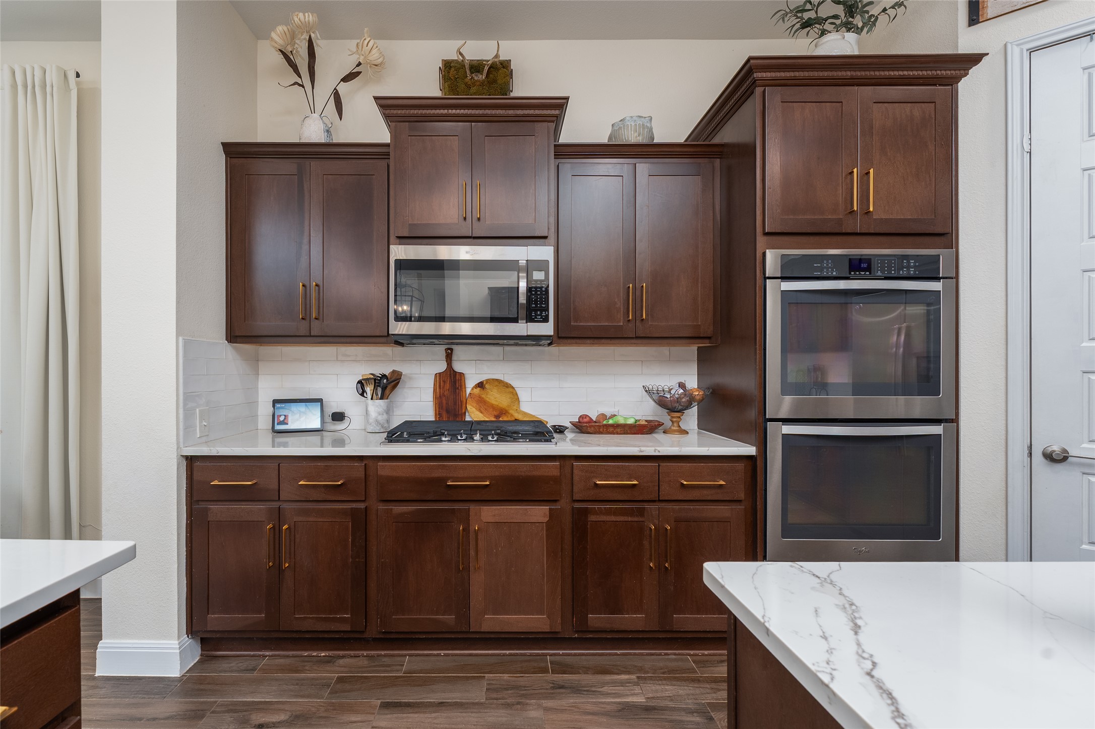 1225 Grassy Field Road Austin, TX 78737 - Photo 33 of 40 Kitchen with stainless steel appliances, decorative backsplash, wood tiled floors, and dark brown cabinetry