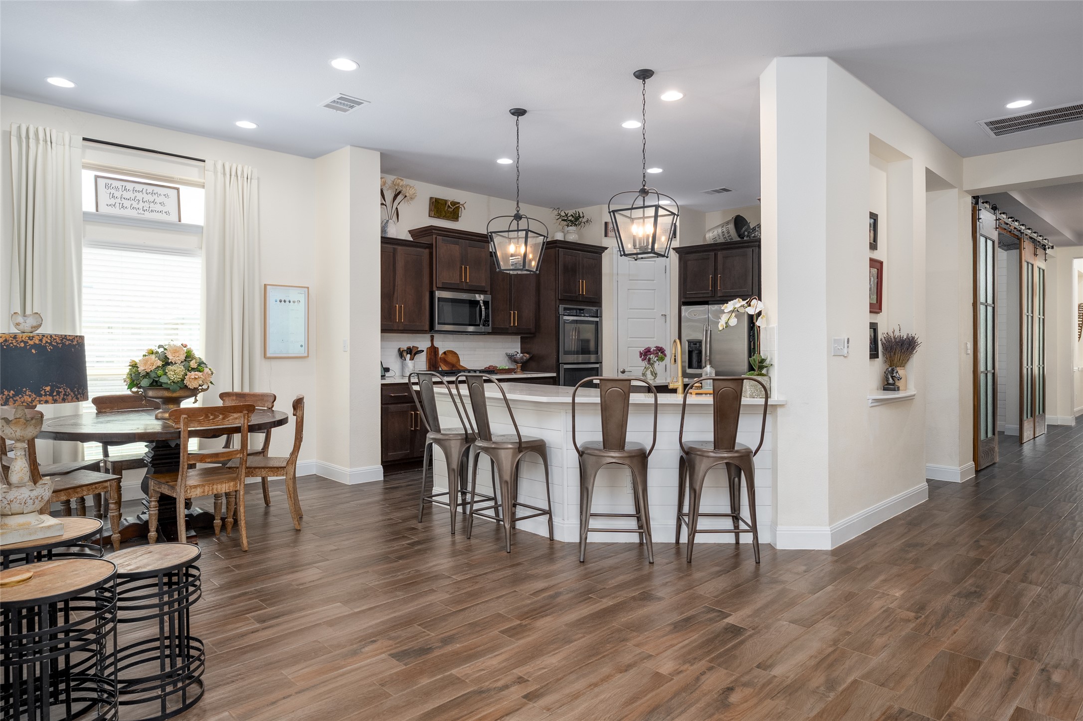 1225 Grassy Field Road Austin, TX 78737 - Photo 36 of 40 Kitchen with appliances with stainless steel finishes, dark brown cabinetry, a peninsula, a kitchen bar, and baseboards