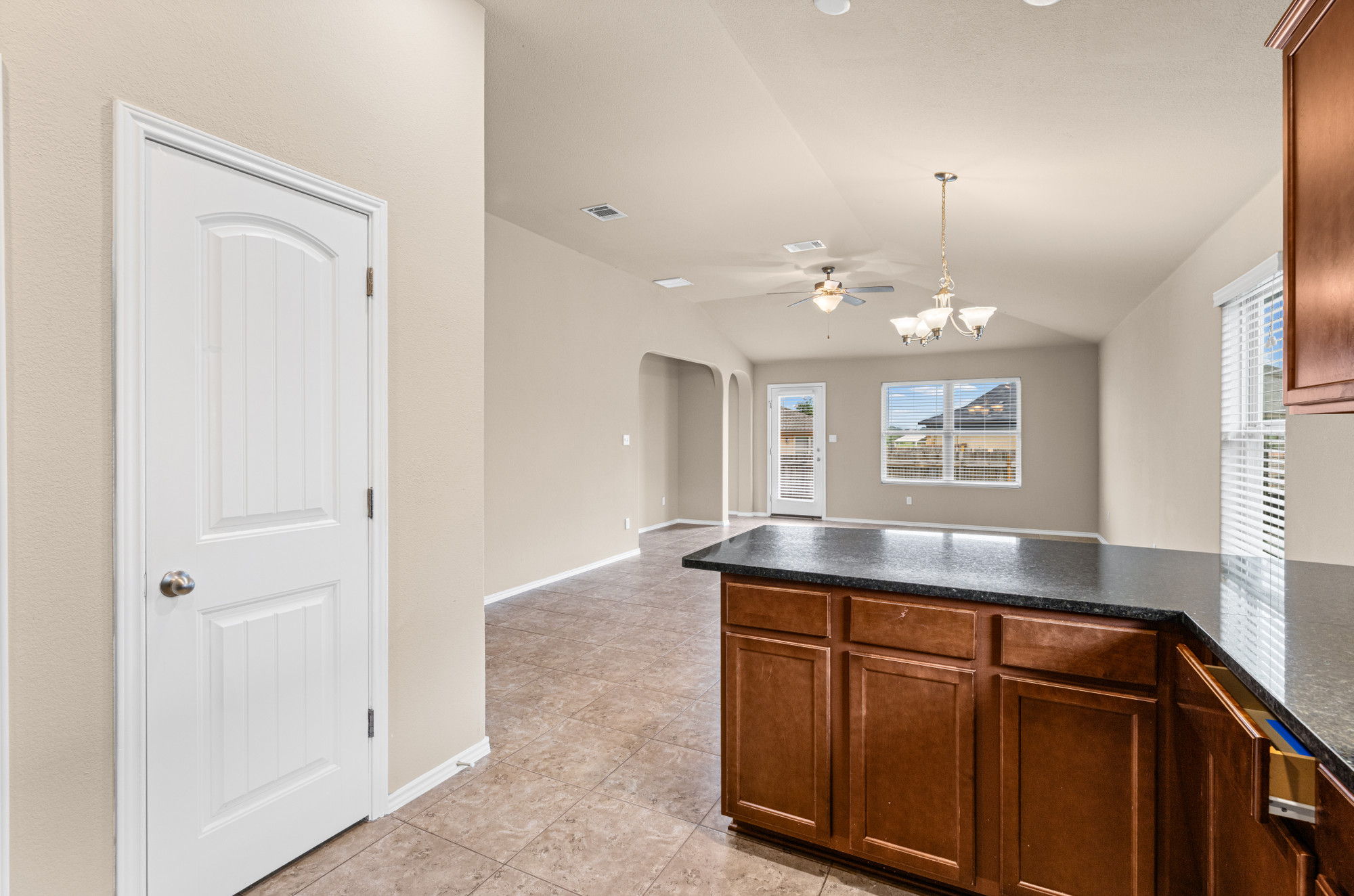 19308 Stokes Lane Pflugerville, TX 78660 - Photo 8 of 27 Kitchen island featuring dark countertops, wood-finish cabinetry, and tile flooring