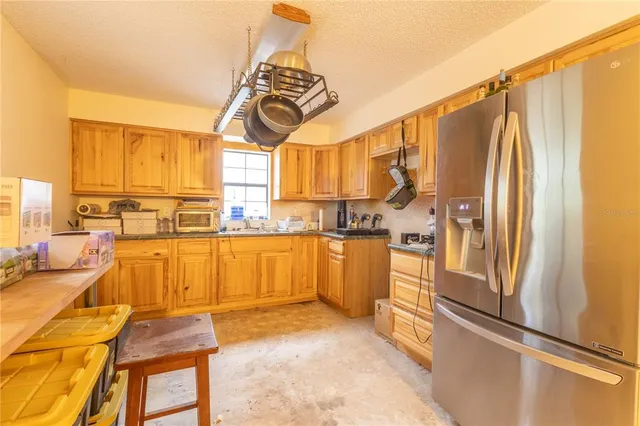 a kitchen with stainless steel appliances granite countertop a refrigerator a sink and white cabinets