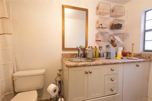 a bathroom with a granite countertop toilet sink and mirror