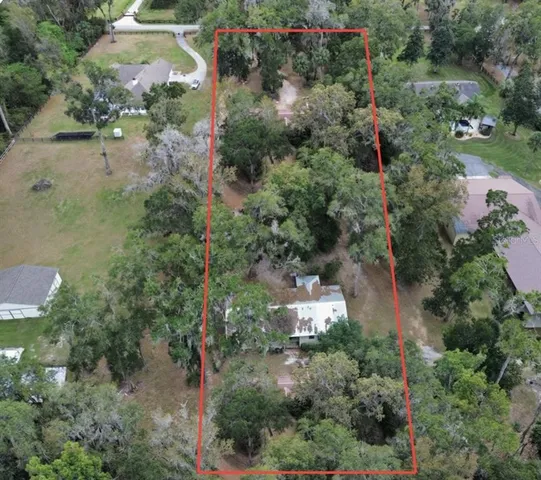 an aerial view of residential house with outdoor space and trees all around