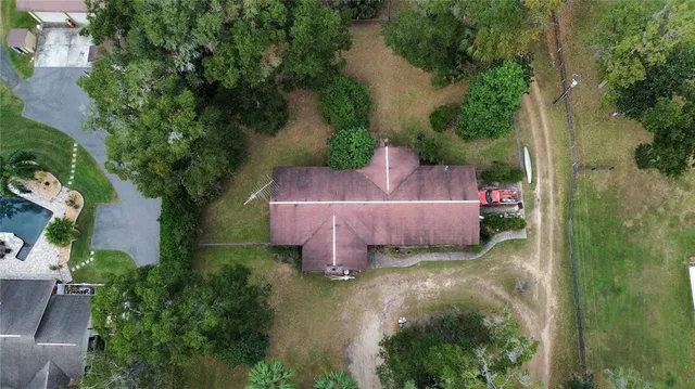 an aerial view of a house with garden space and trees all around