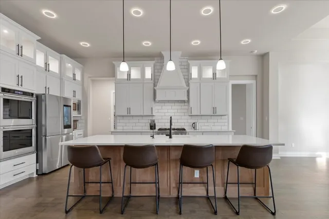 a kitchen with stainless steel appliances granite countertop a sink a stove and a refrigerator