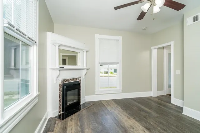 an empty room with wooden floor fan and windows