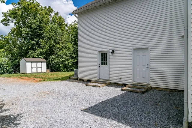 a view of a house with a yard and large tree