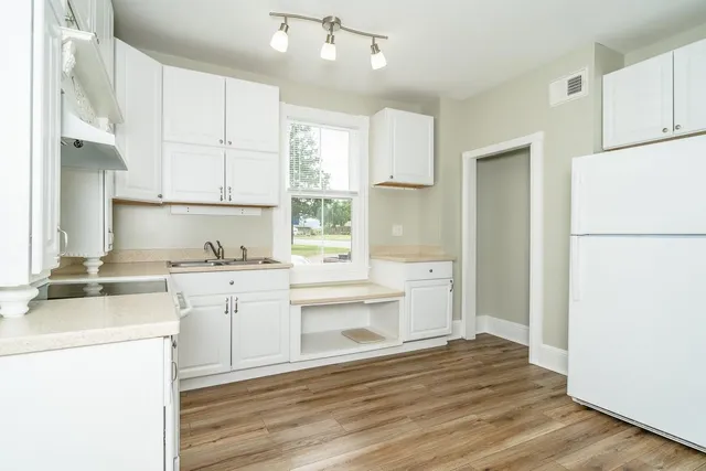 a kitchen with granite countertop a refrigerator sink stove and white cabinets