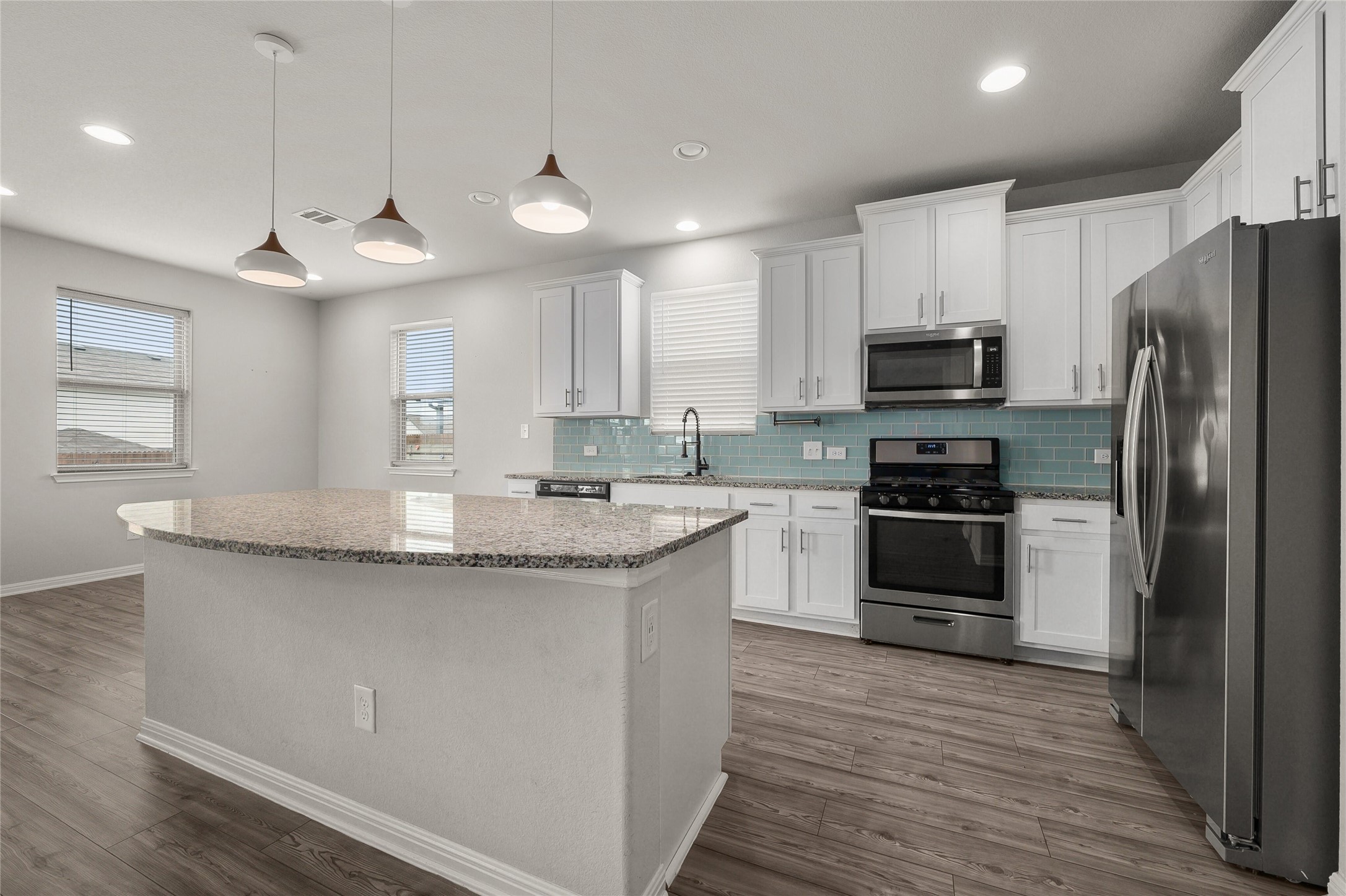101 Lambert Street Leander, TX 78641 - Photo 8 of 33 A well-lit culinary space features a spacious granite-topped island and gleaming stainless steel appliances.