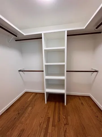 a view of walk in closet with wooden floor