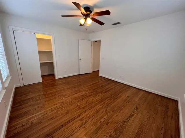 a view of a big room with wooden floor and a chandelier fan