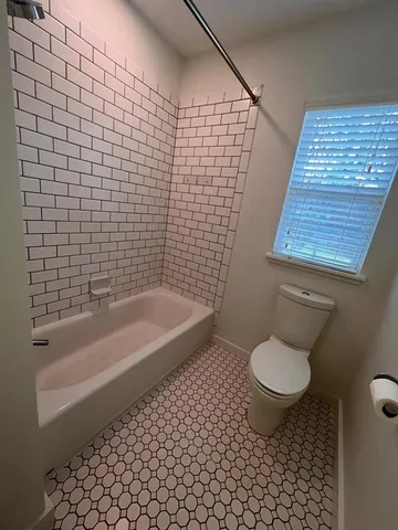 a bathroom with a granite countertop toilet and a bathtub