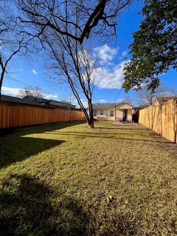 a view of yard with large tree and wooden fence