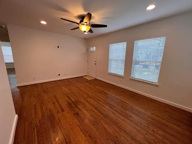 a view of an empty room with wooden floor and a window