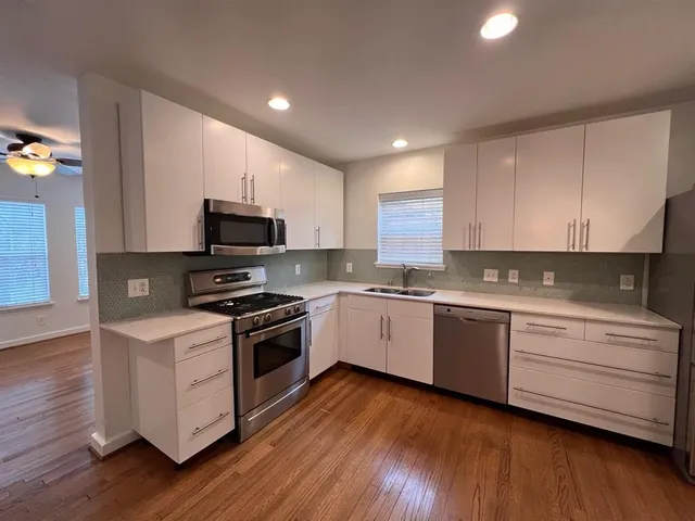 a kitchen with granite countertop wooden floors and white stainless steel appliances