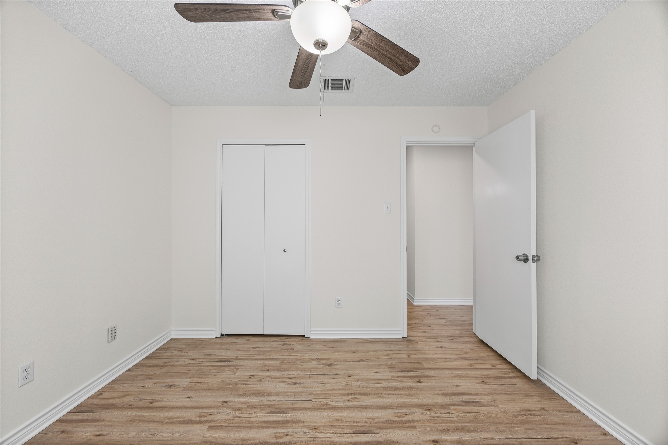 806 Calico Drive Austin, TX 78748 - Photo 15 of 25 Unfurnished bedroom featuring light wood-style floors, a ceiling fan, a closet, and a textured ceiling