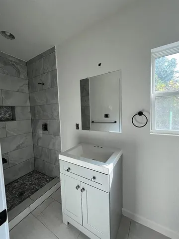 a spacious bathroom with a granite countertop sink a mirror and shower