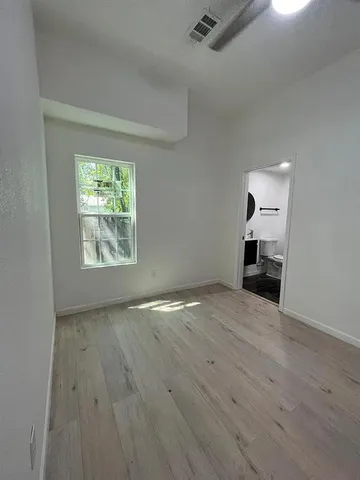 an empty room with wooden floor cabinet and windows